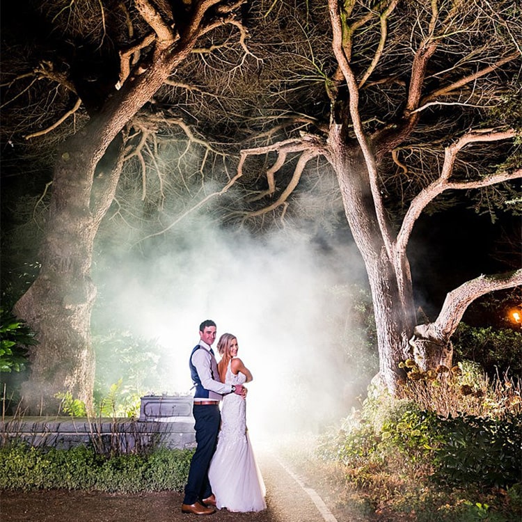 A bride and groom stand infront of a white steam backdrop at Clontarf Castle Wedding Venue in Dublin.
